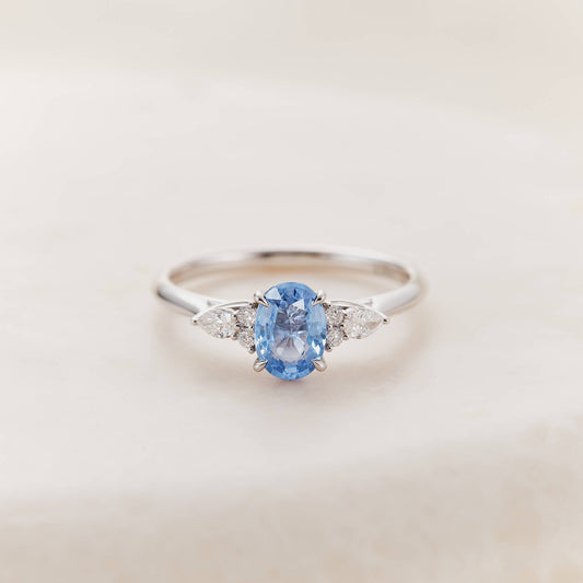 The White Gold ring features a smooth, polished, slender band and is displayed against a soft, minimalist, neutral beige background.