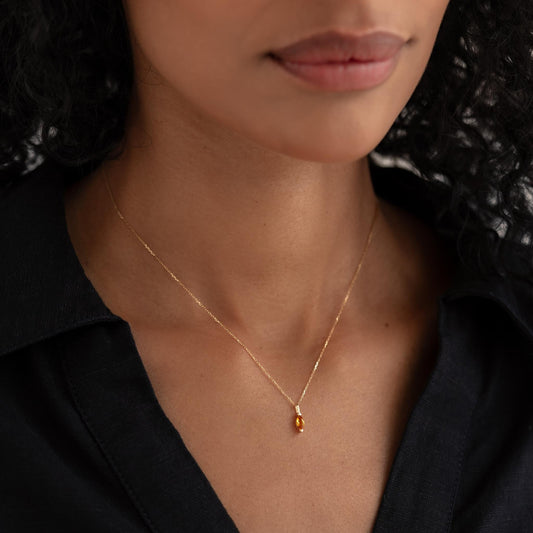 Close-up of a woman wearing the November Birthstone Pendant 14k Gold - Citrine on a delicate gold chain with black top