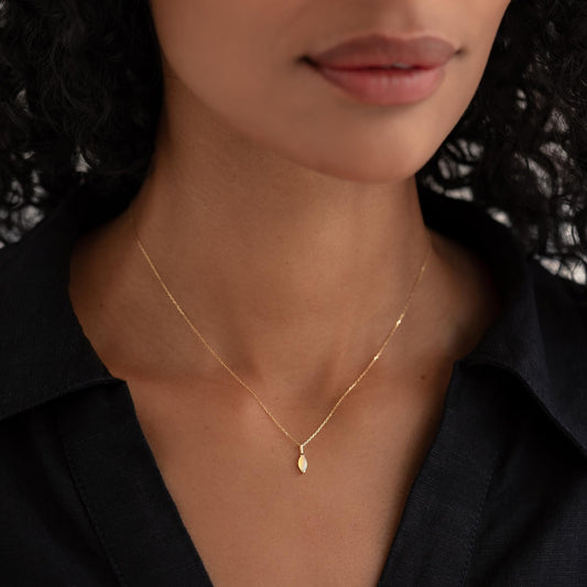Close-up of woman wearing October Birthstone Pendant 14k Gold - Opal with a black collared shirt on a neutral background