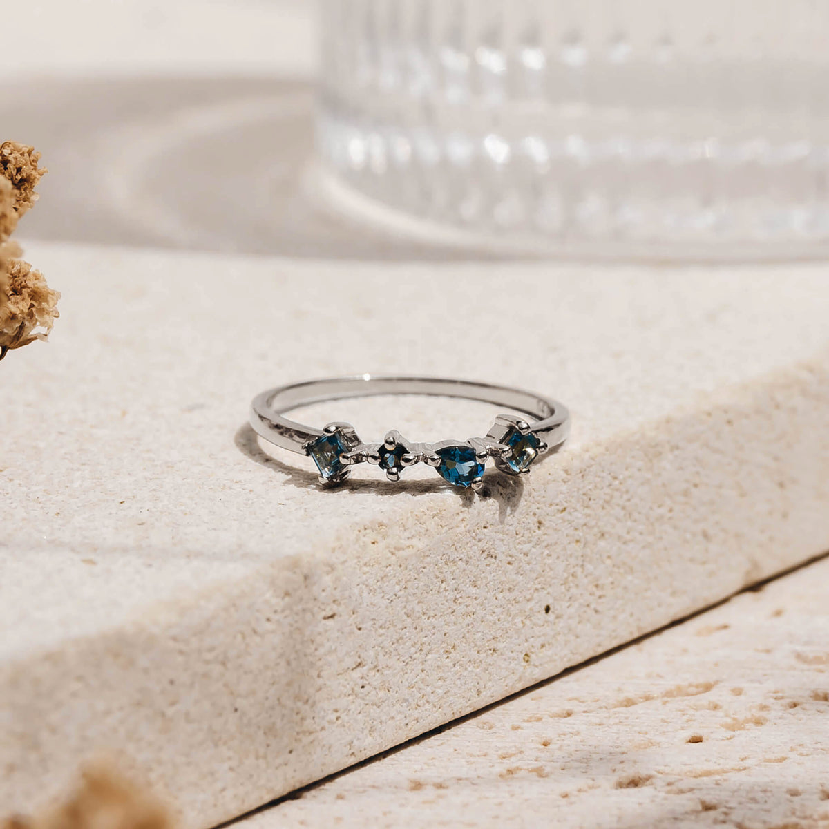 White Gold London Blue Topaz Ring - Ilse Luxe with four unique hand-cut blue topaz stones on a light textured surface