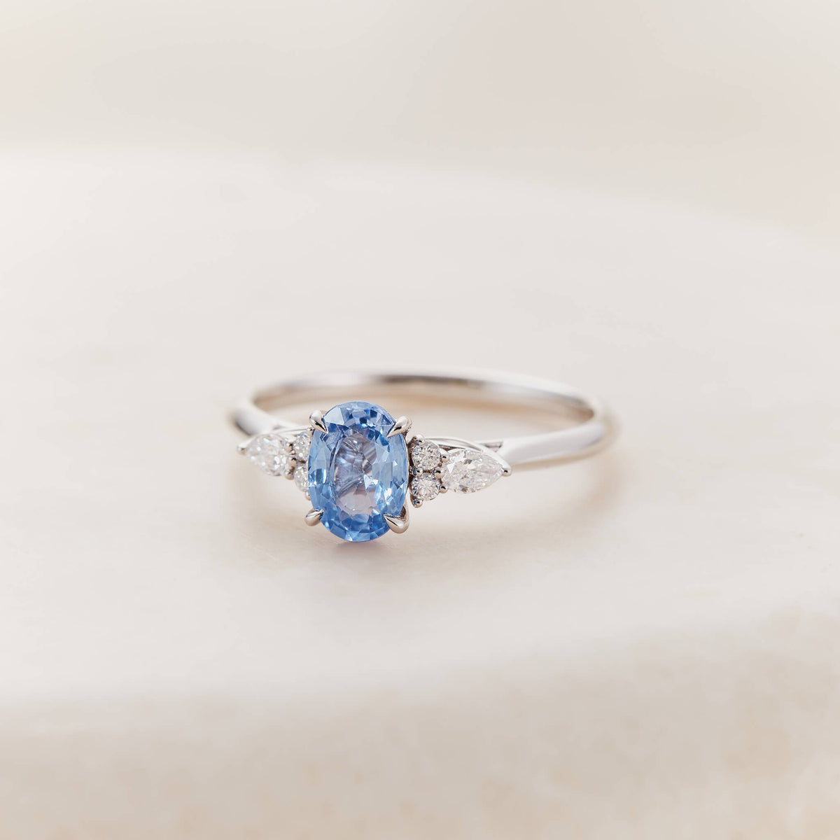 An elegant White Gold ring centered with a vibrant, oval-cut cornflower blue sapphire.