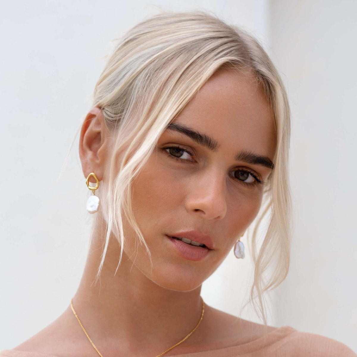 Statement pearl earrings with organic gold setting on model