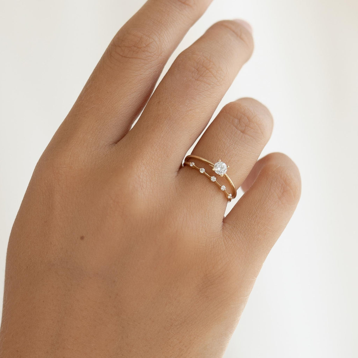 Close-up of a hand wearing the Five Stone Diamond Ring 14k Gold - Leoni with five sparkling diamonds on a gold band