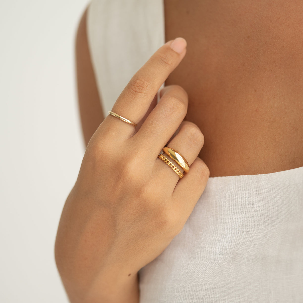 Close-up of hand wearing Dome Ring - Arielle with a tapered puffy gold vermeil design and two gold stacking rings