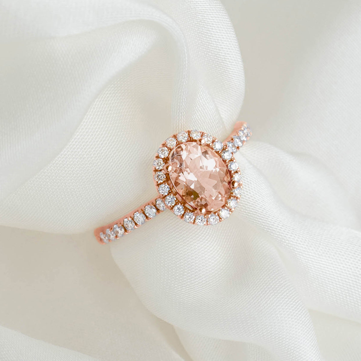 Oval Morganite Halo Ring Rose Gold - Suna featuring pavé diamonds and an oval morganite gemstone on a soft fabric background