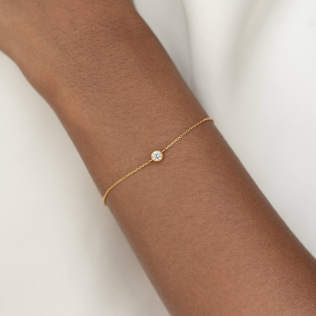Delicate Gold Vermeil chain bracelet with a small round White topaz gemstone centerpiece, worn around a woman's wrist.