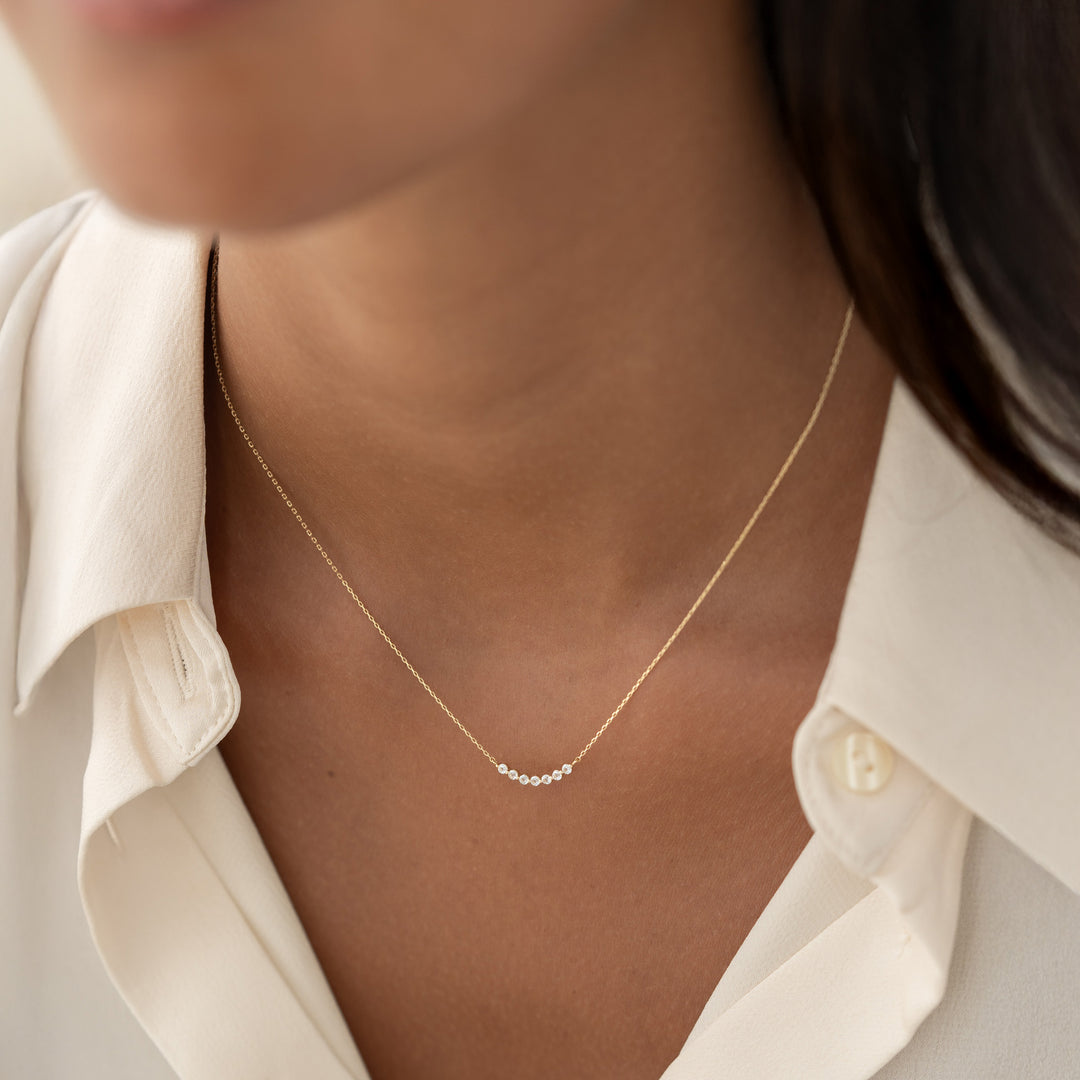 Close-up of a woman wearing April Birthstone Necklace 14k Gold - Diamond with a delicate curved diamond bar on gold chain