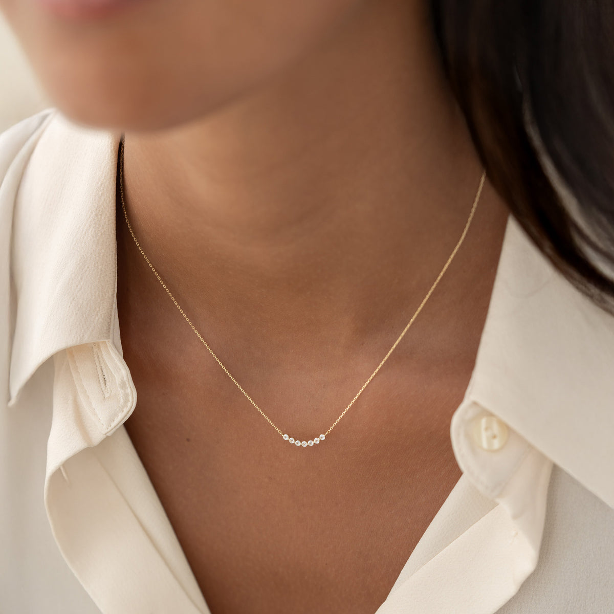 Close-up of a woman wearing April Birthstone Necklace 14k Gold - Diamond with a delicate curved diamond bar on gold chain
