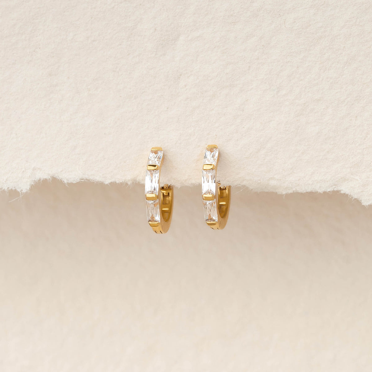 Pair of Gold Vermeil earrings set with baguette-cut gemstone, displayed hanging against a soft, textured ivory background.