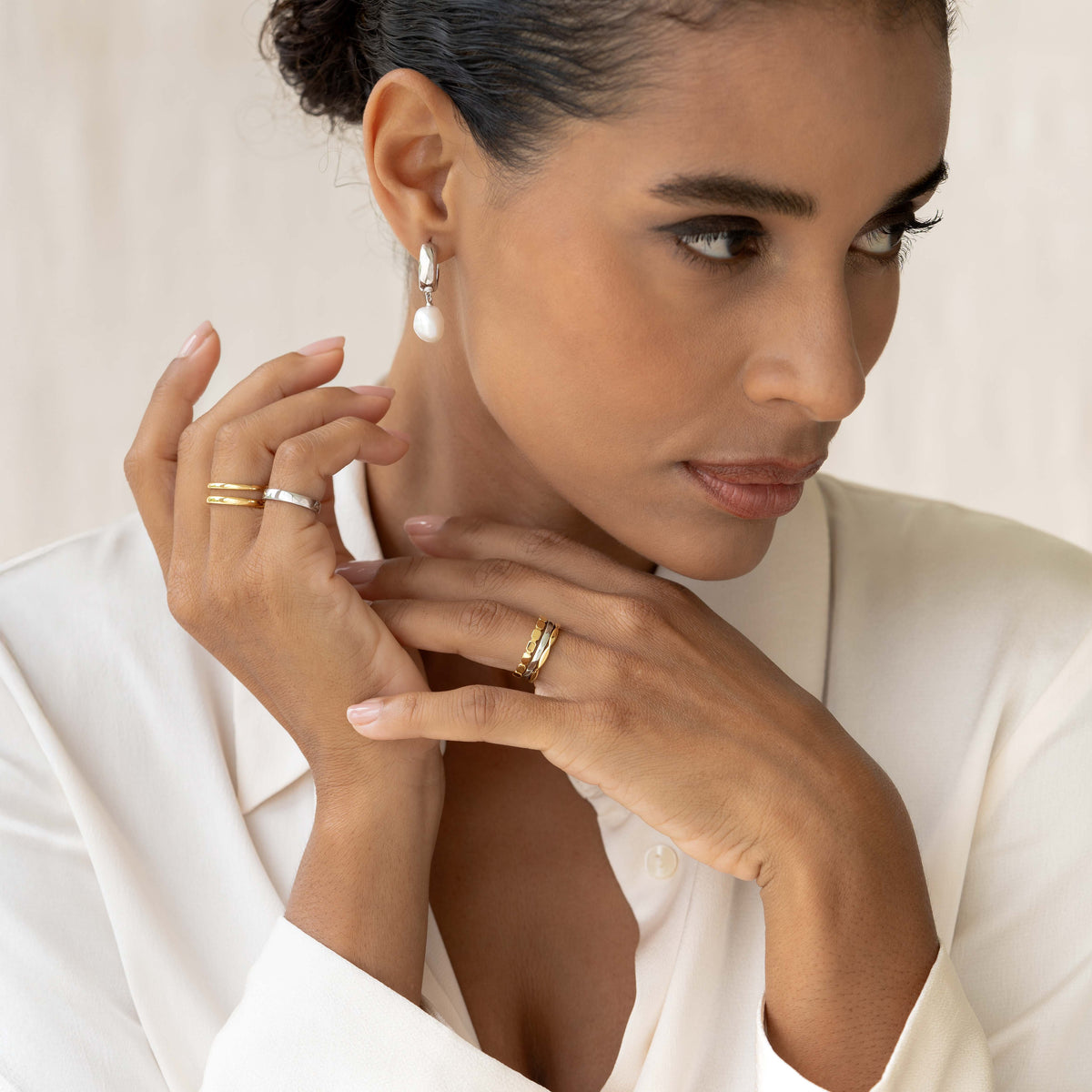 Woman wearing Baroque Pearl Chunky Hoop Earrings Silver - Meredith with gold and silver rings and white blouse