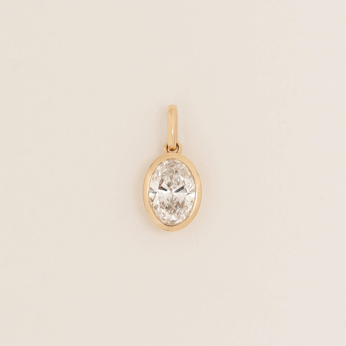 Yellow Gold oval shaped pendant with a polished finish, shown against a light neutral background.