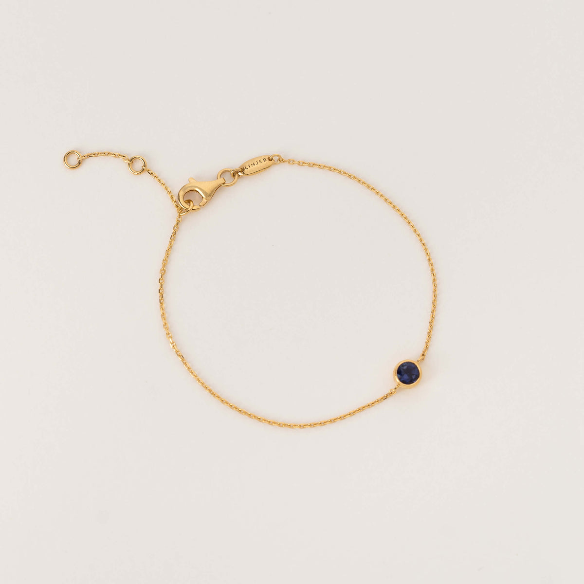 Delicate Gold Vermeil chain bracelet with an adjustable clasp and a single round Cordierite gemstone set in a gold bezel, displayed on a clean white background.