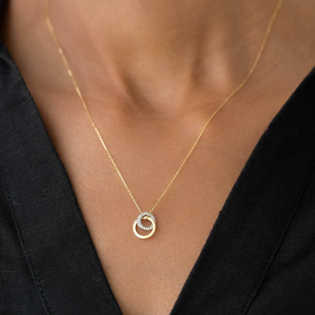 Diamond Double Circle Necklace 14k Gold - Diana with two interlocking rings on a gold chain worn on black top