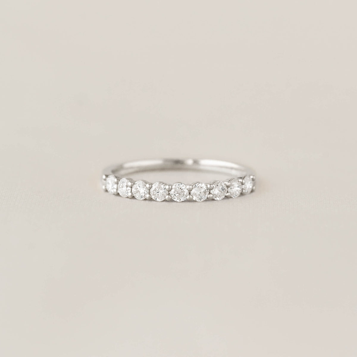 Elegant White Gold ring with a row of sparkling diamonds, set against a soft, neutral background. The design exudes simplicity and sophistication.