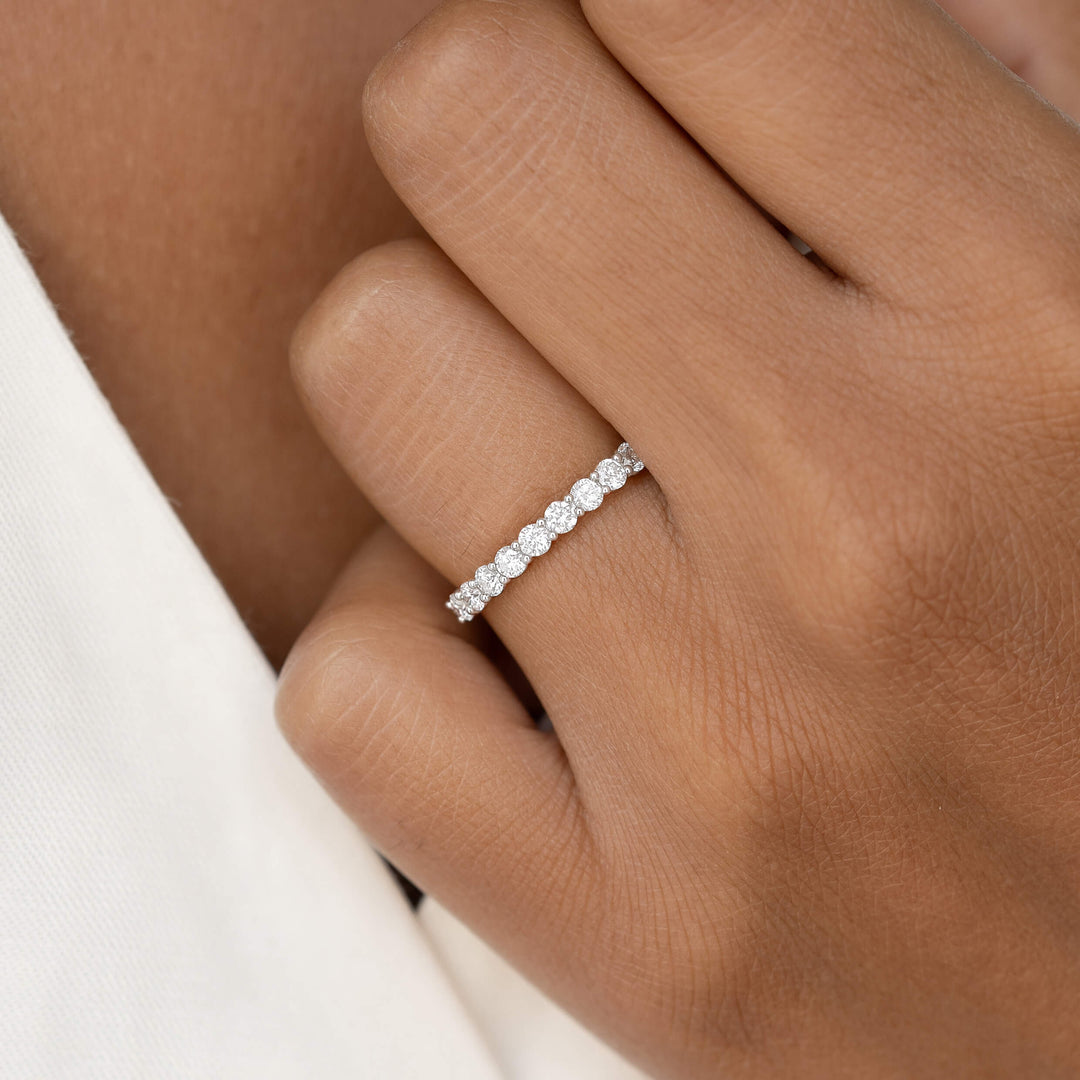 Close-up of a hand wearing a White Gold ring adorned with round sparkling diamonds on the ring finger.