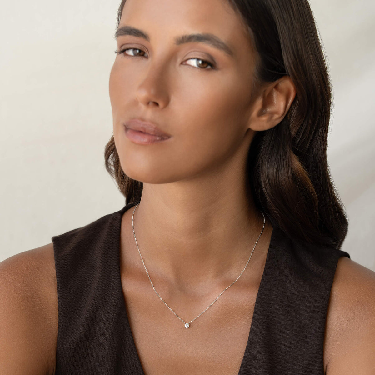 Close-up portrait of a woman wearing a delicate White Gold necklace, showcasing elegance and beauty against a neutral background.