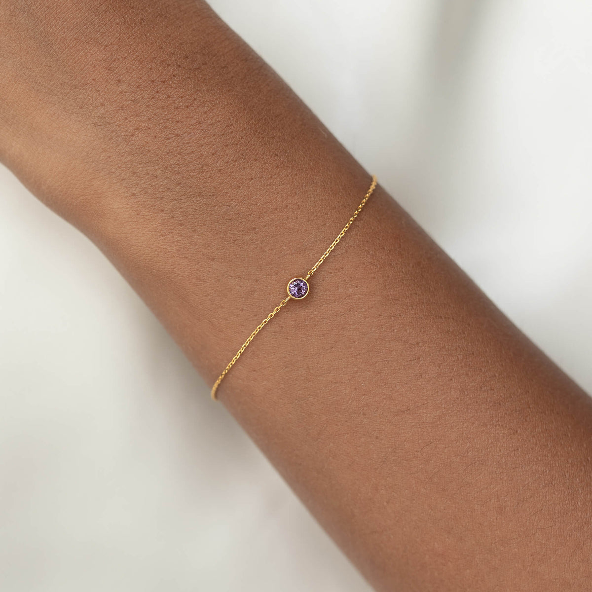 Delicate Gold Vermeil chain bracelet with a small round Amethyst gemstone centerpiece, worn around a woman's wrist.