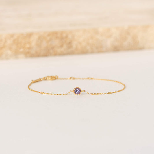 Delicate Gold Vermeil chain bracelet featuring a small round Amethyst gemstone centerpiece, laid flat on a light-colored surface.