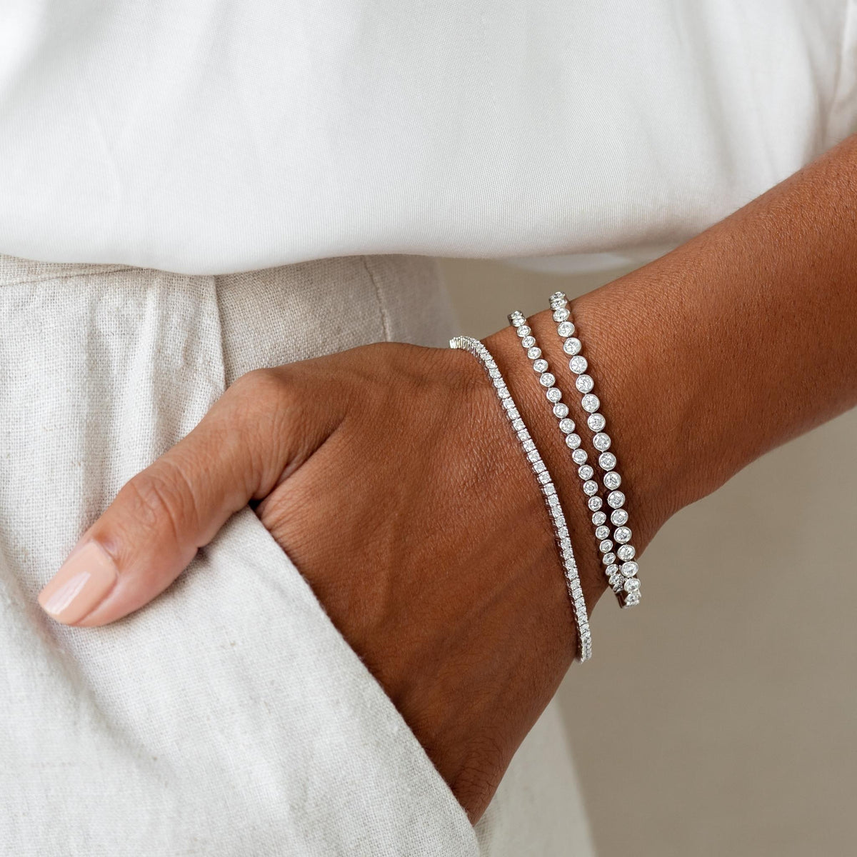 Close-up of a wrist wearing the Half Diamond Tennis Bracelet 14k White Gold (1.8 - 2.0 ct tw) with layered bracelets