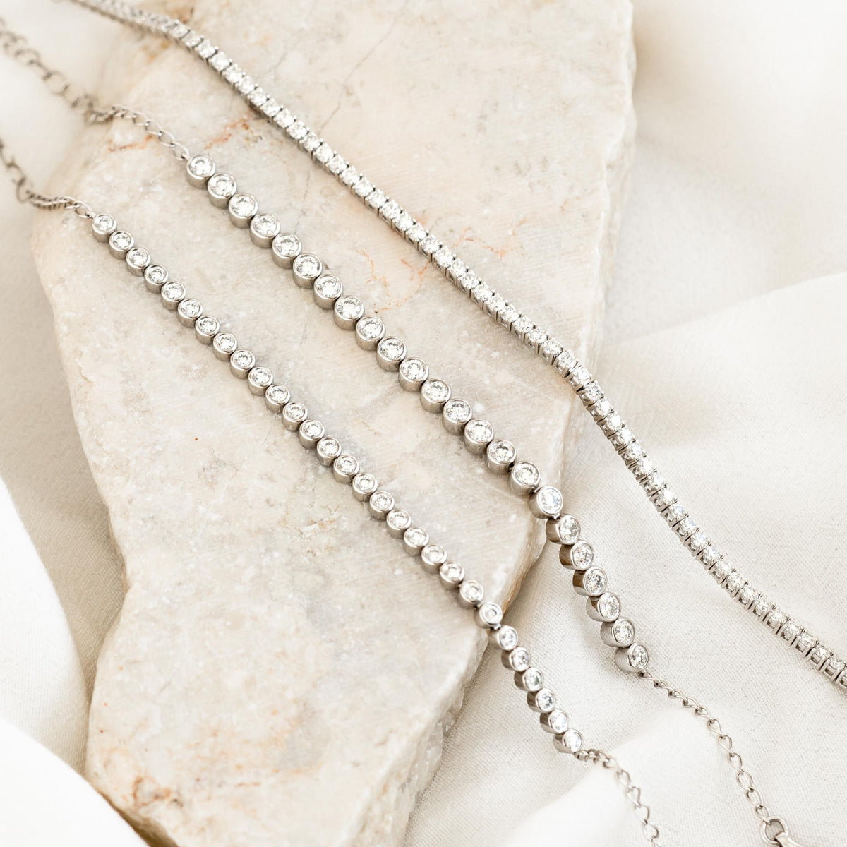 Half Diamond Tennis Bracelet 14k White Gold (1.8 - 2.0 ct tw) displayed on marble and fabric background