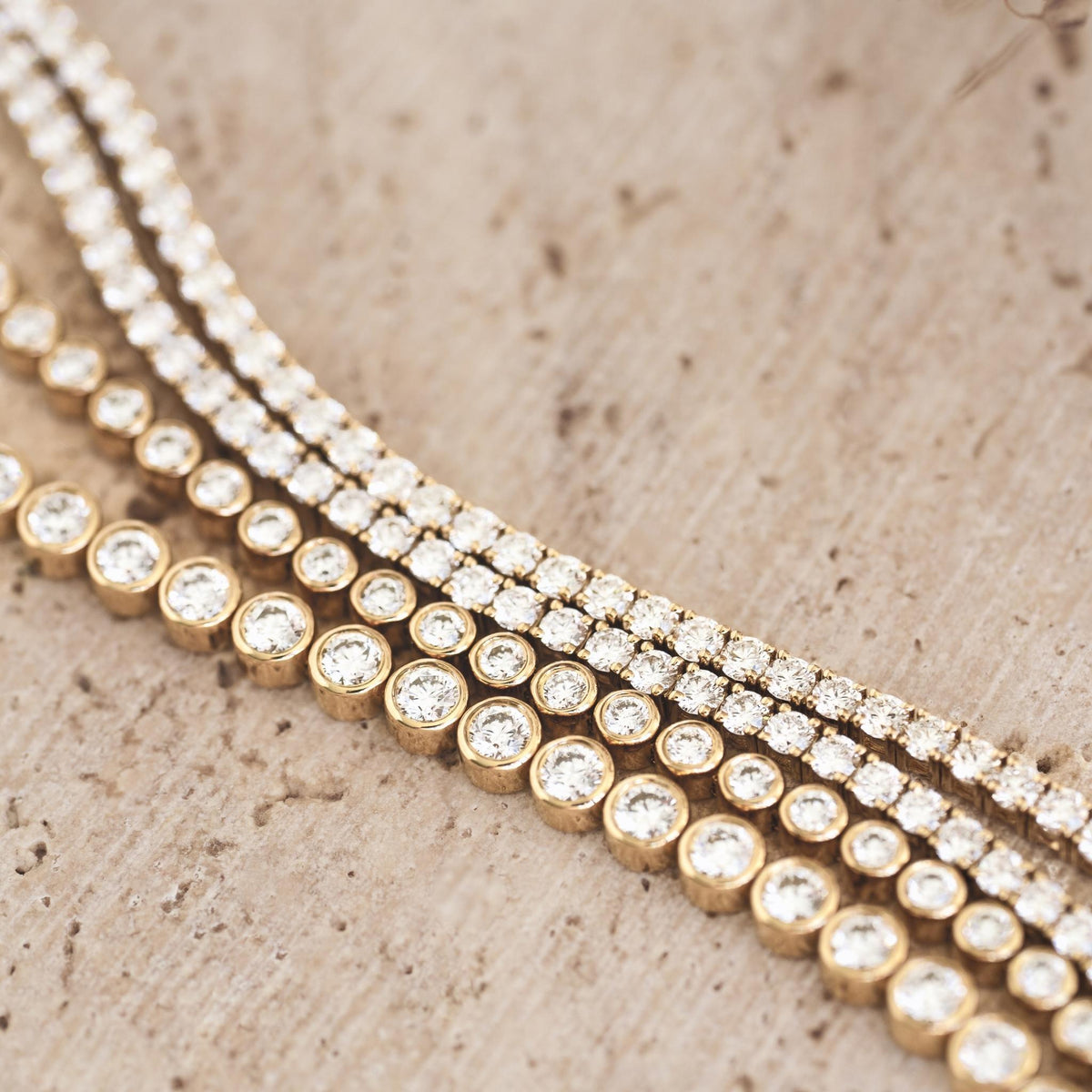 Half Diamond Tennis Bracelet 14k Yellow Gold (1.8 - 2.0 ct tw) with bezel-set round diamonds on a beige surface