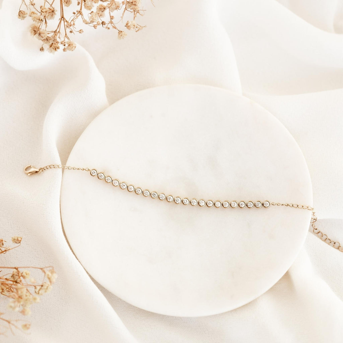 Half Diamond Tennis Bracelet 14k Yellow Gold (1.8 - 2.0 ct tw) displayed on round white marble with soft neutral fabric background