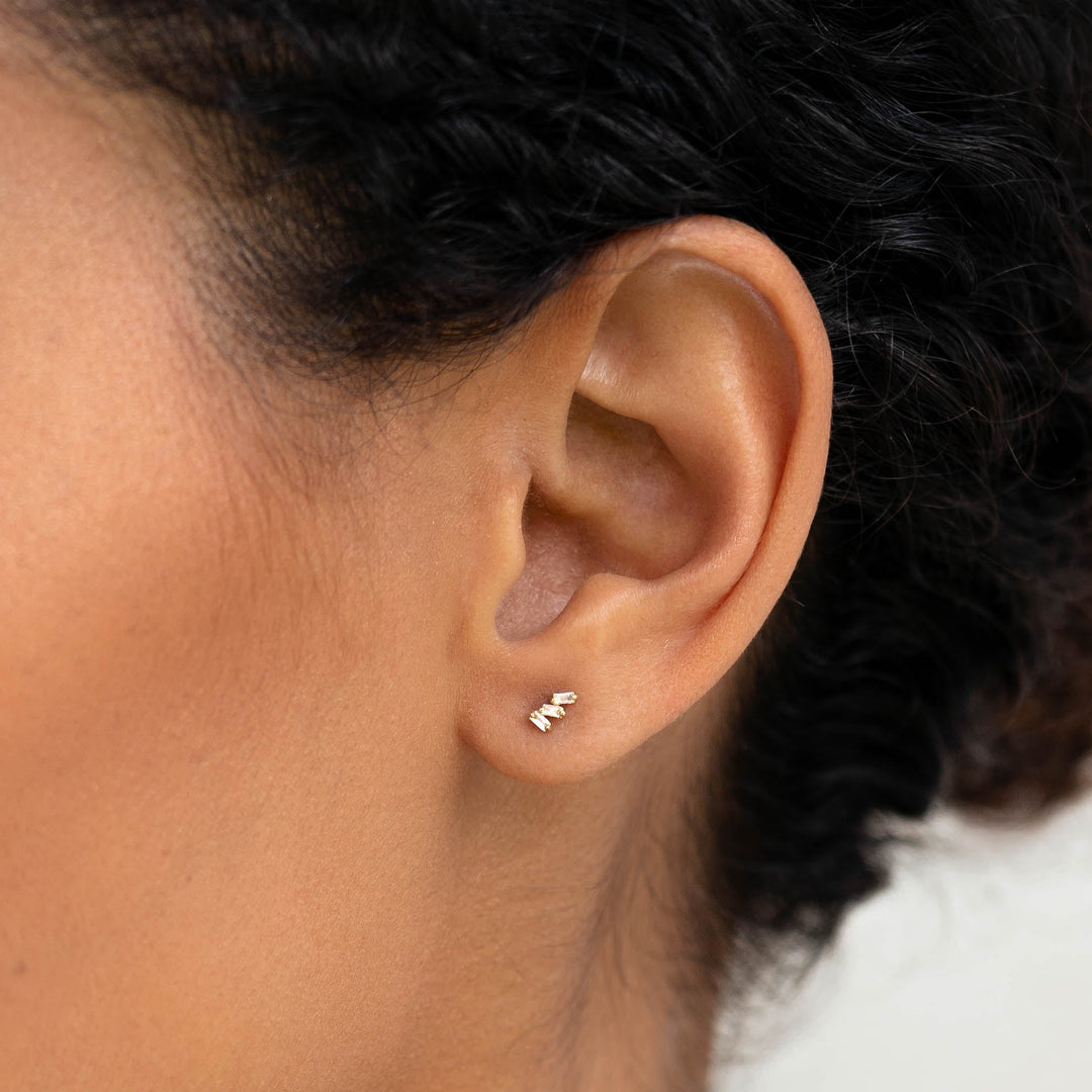 Close-up of a woman wearing Baguette Cluster Gemstone Stud Earrings - Lovise with white topaz stones and gold vermeil setting