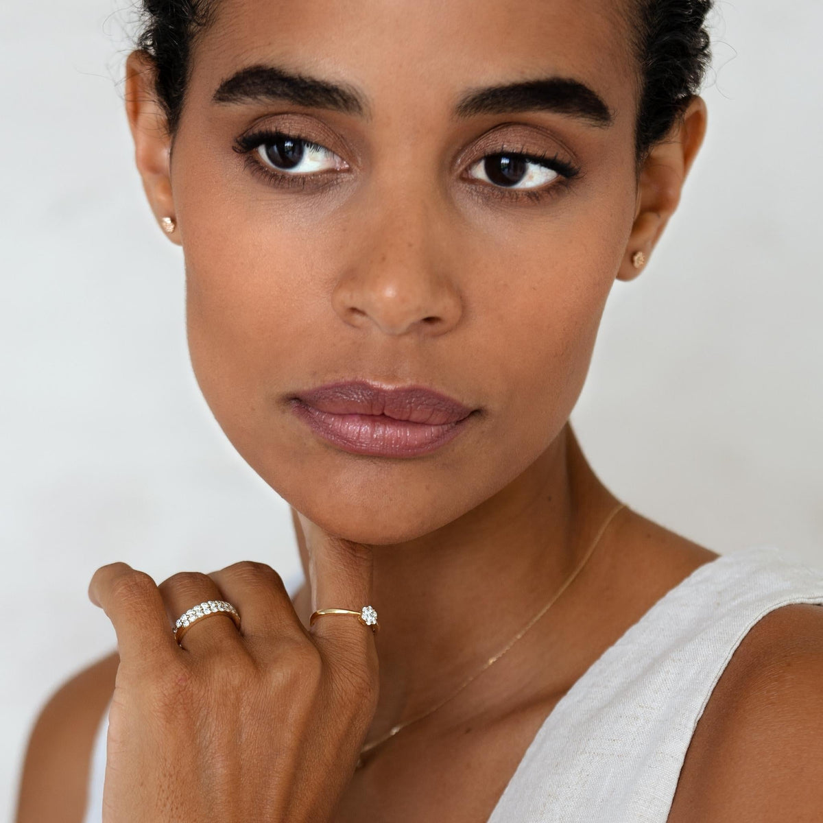 Close-up of woman wearing the Diamond Half Eternity Ring 14k Gold - Isa on her finger with a white sleeveless top