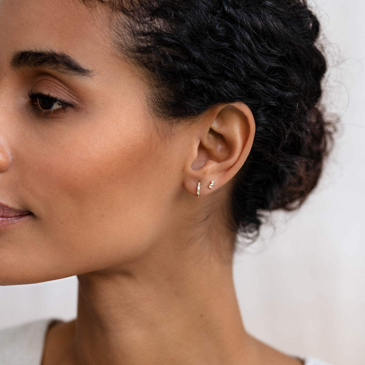 Close-up of a woman wearing Baguette Cluster Gemstone Stud Earrings - Lovise with gold vermeil setting on her ear