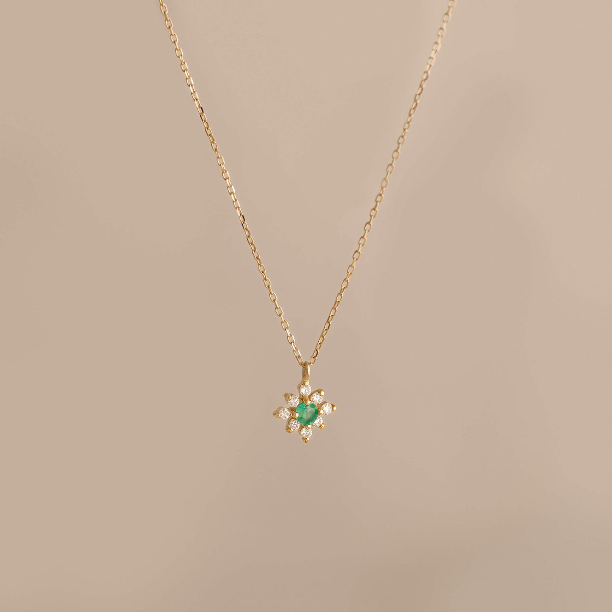 Emerald Flower Pendant Necklace 14k Gold - Inga featuring a delicate chain and emerald diamond flower pendant on beige background
