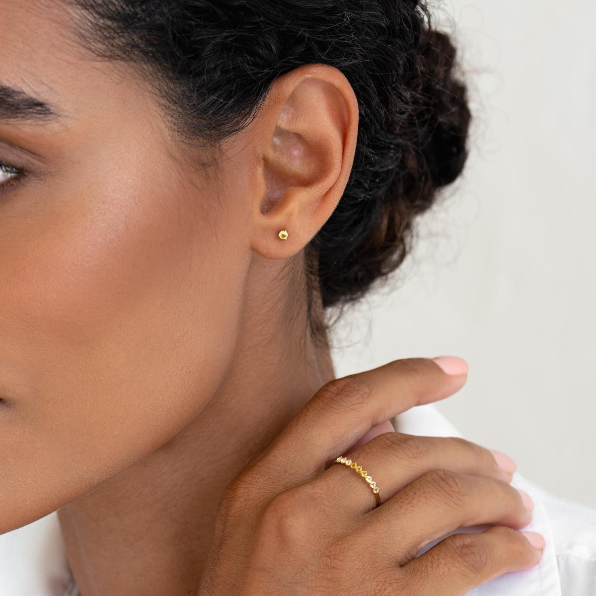 Close-up of woman wearing November Birthstone Stud Earrings 14k Gold - Citrine with a minimalist gold ring on neutral background