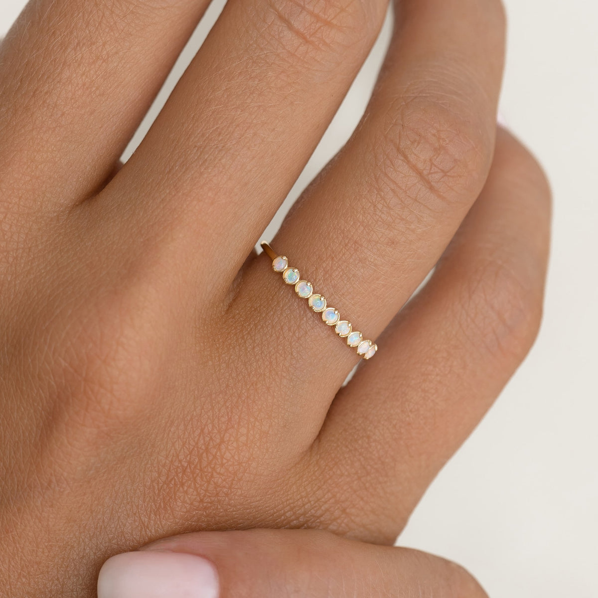 October Birthstone Ring 14k Gold - Opal featuring nine small opal gemstones on a hand with neutral background