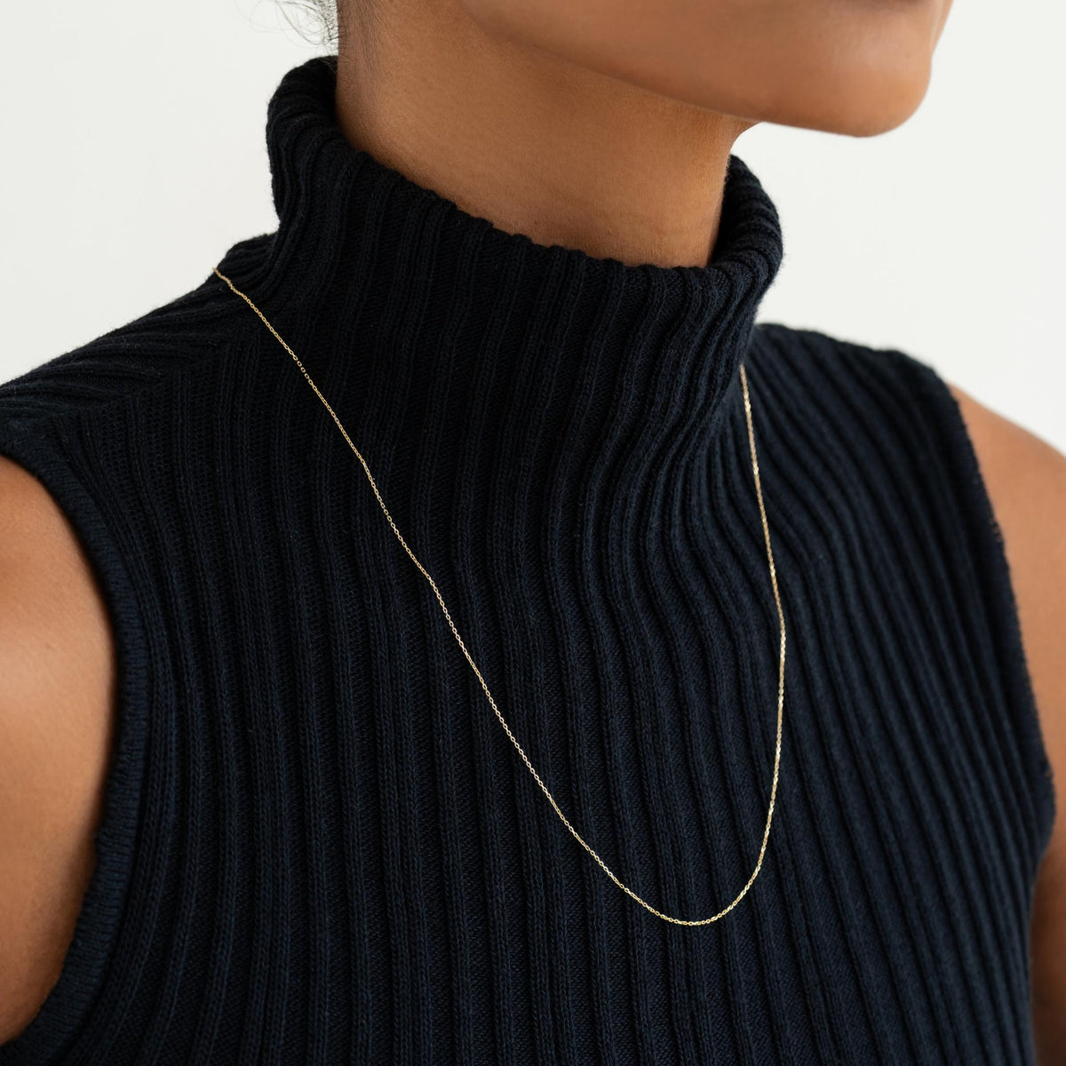 Close-up of a woman wearing the 14k Gold Cable Chain Necklace (20 inches) - Tyra with a black ribbed turtleneck