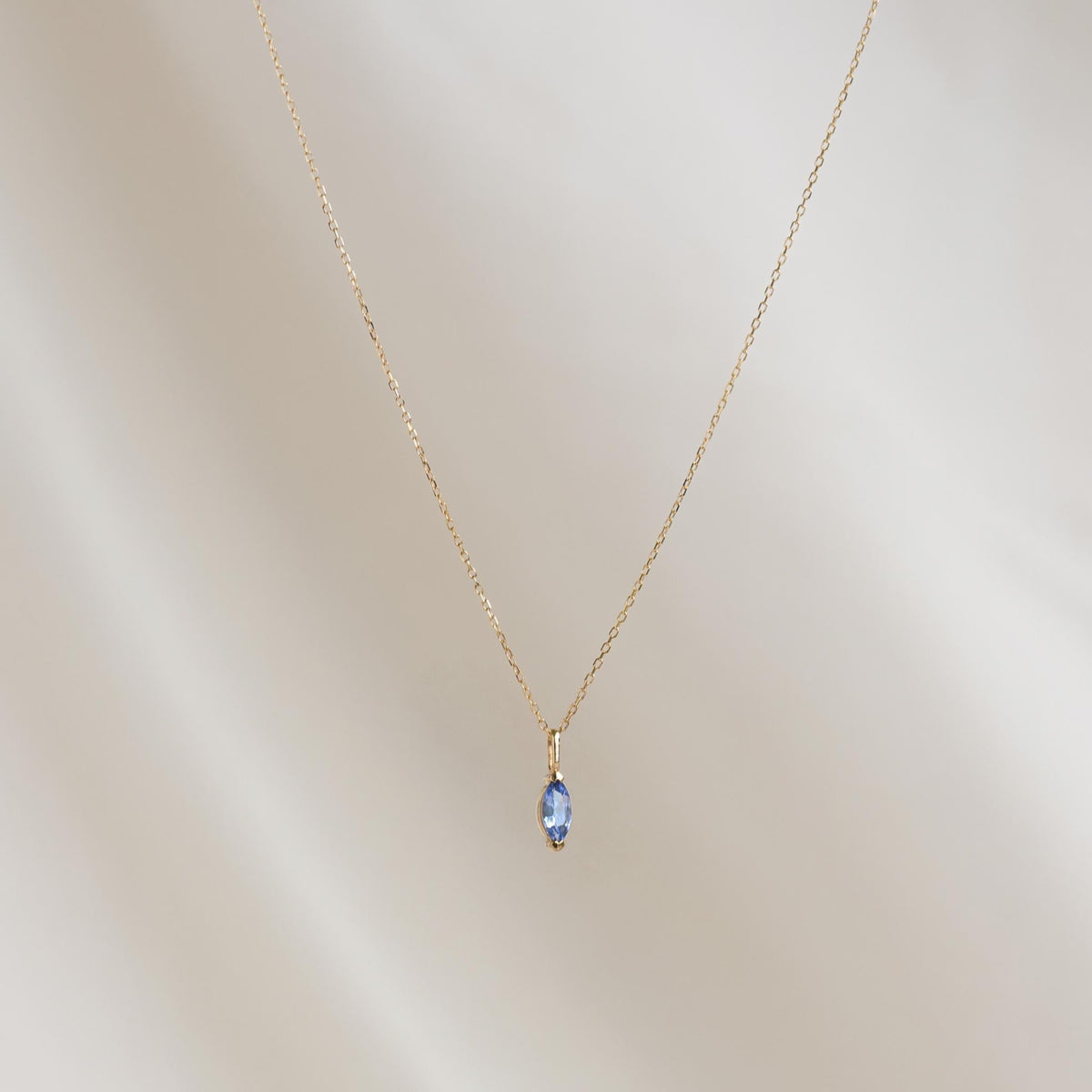 December Birthstone Pendant 14k Gold - Tanzanite marquise-cut gemstone on a delicate gold chain against a soft background