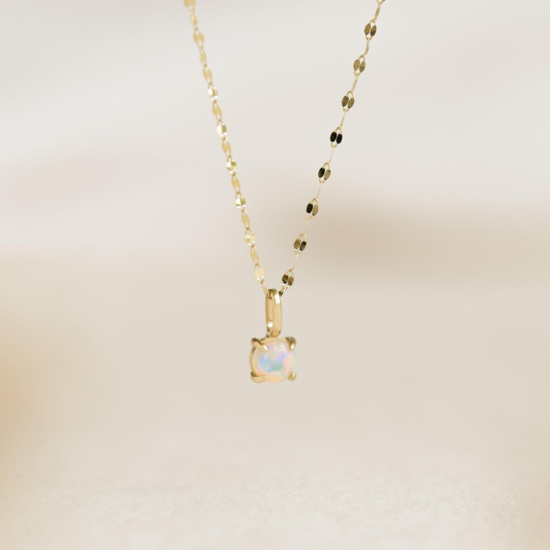 Opal Charm 14k Gold necklace with an iridescent opal pendant on a delicate yellow gold chain on a neutral background