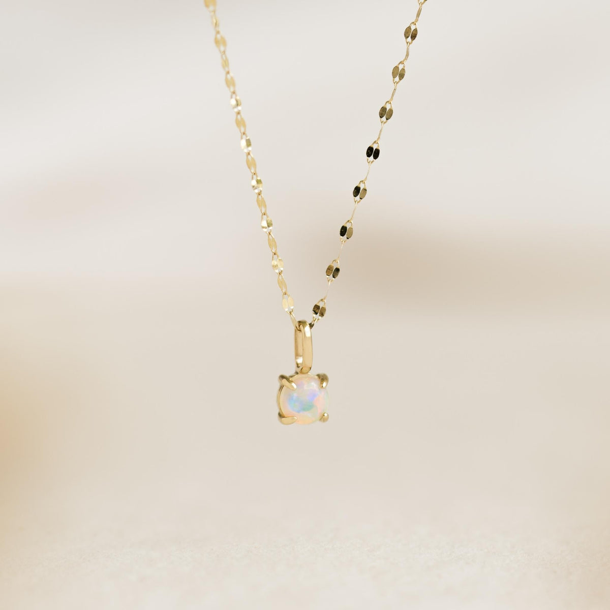 Opal Charm 14k Gold necklace with an iridescent opal pendant on a delicate yellow gold chain on a neutral background