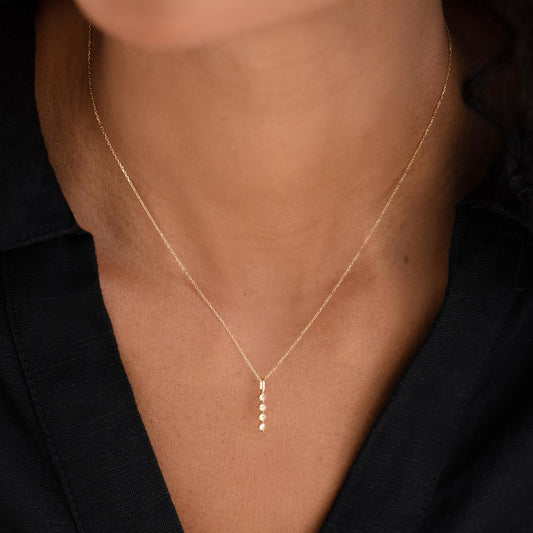 Close-up of woman wearing Diamond Drop Pendant 14k Gold on a delicate yellow gold chain with a black top