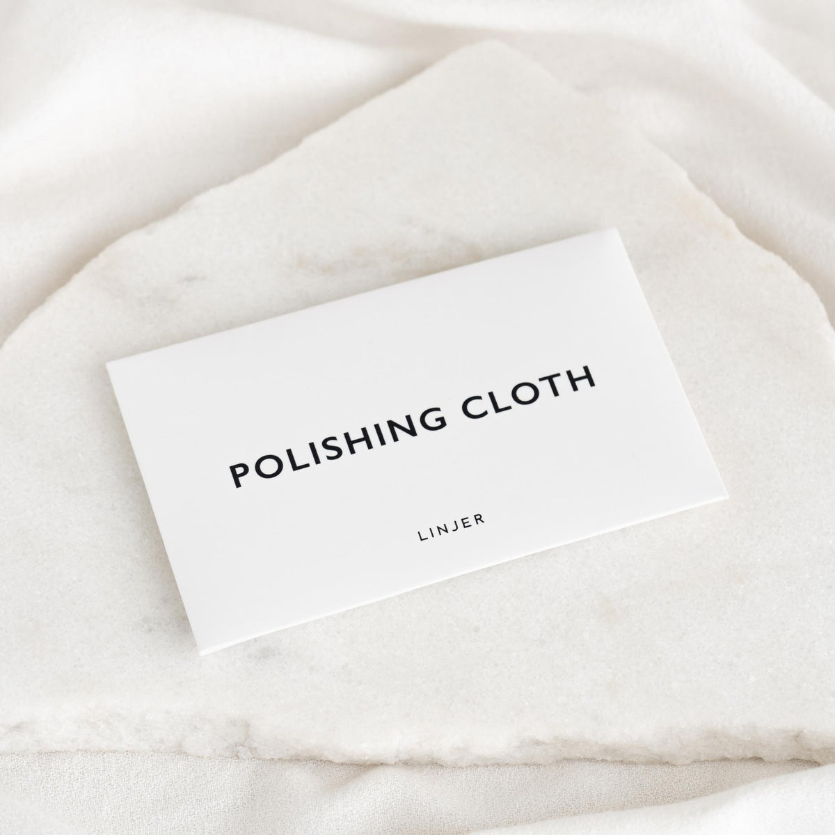 Jewelry Polishing Cloth packaging displayed on a white marble surface with soft natural lighting