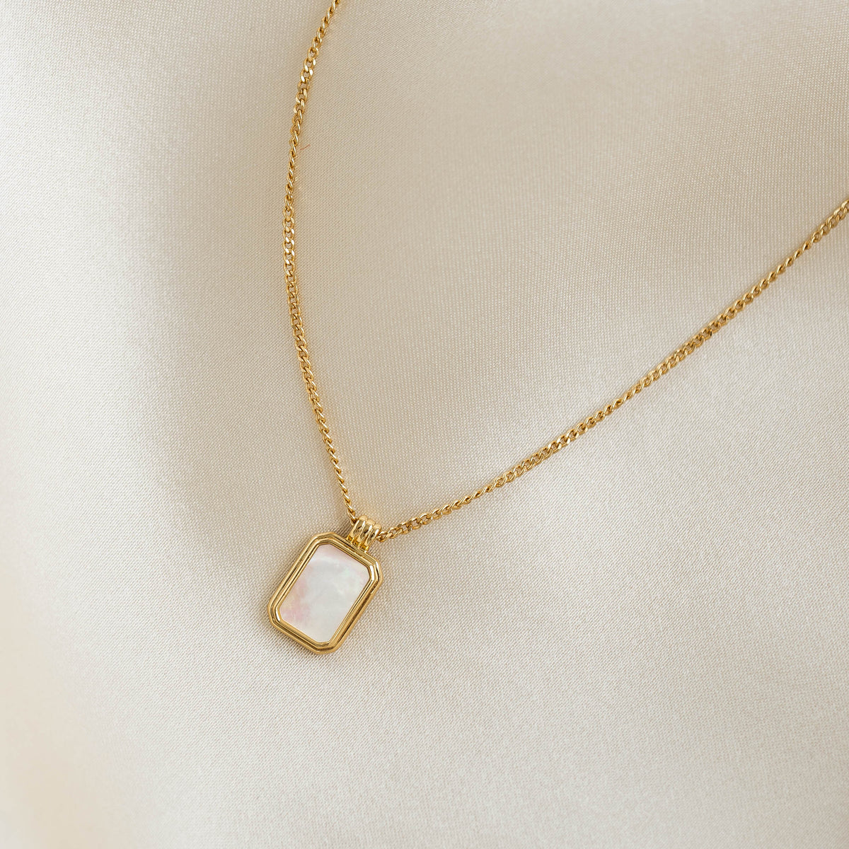 Mother of Pearl Tag Necklace - Iria with rectangular iridescent pendant on a delicate gold vermeil chain on cream fabric background