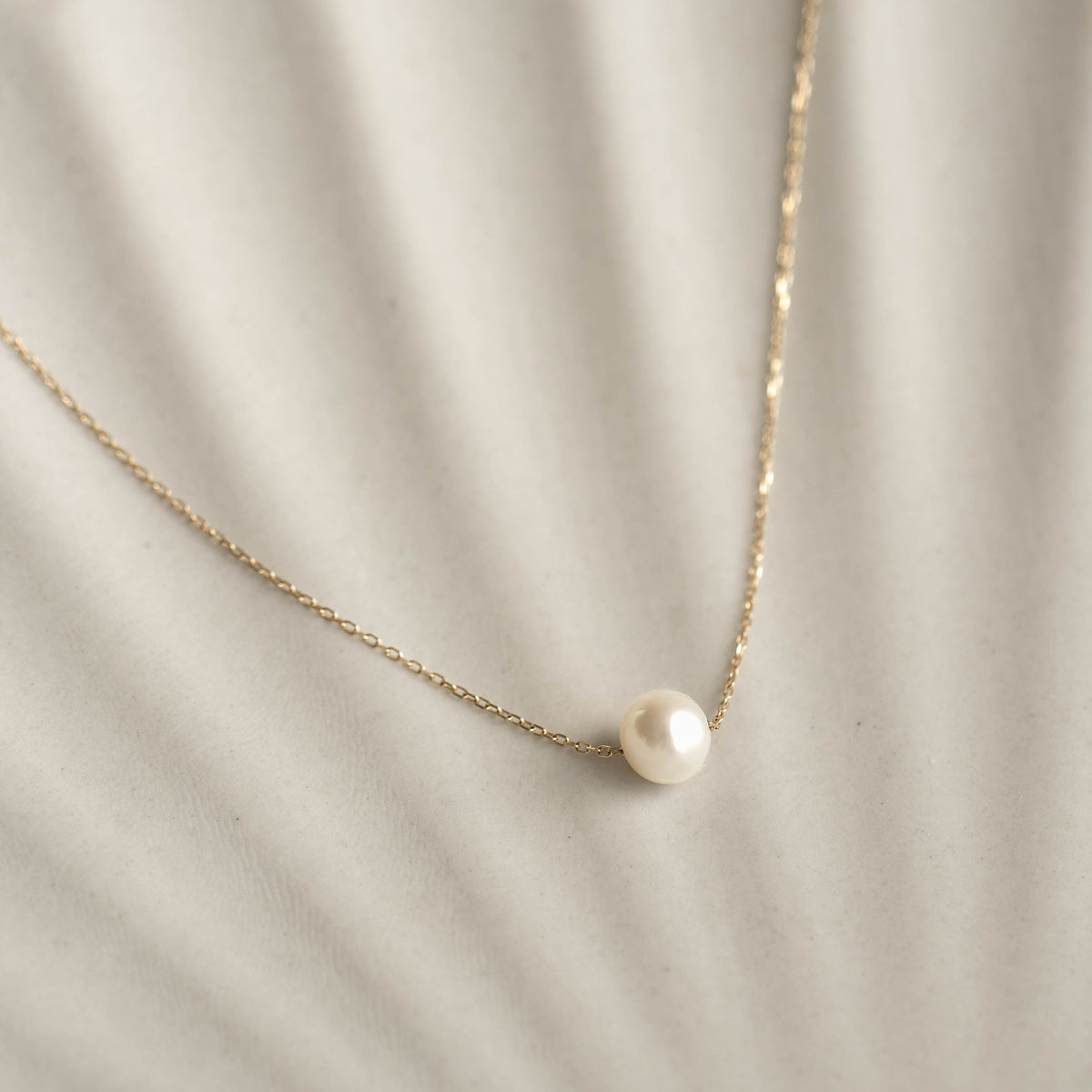 Close-up of Floating Pearl Necklace - Caris featuring a single lustrous pearl on a delicate 14k gold chain