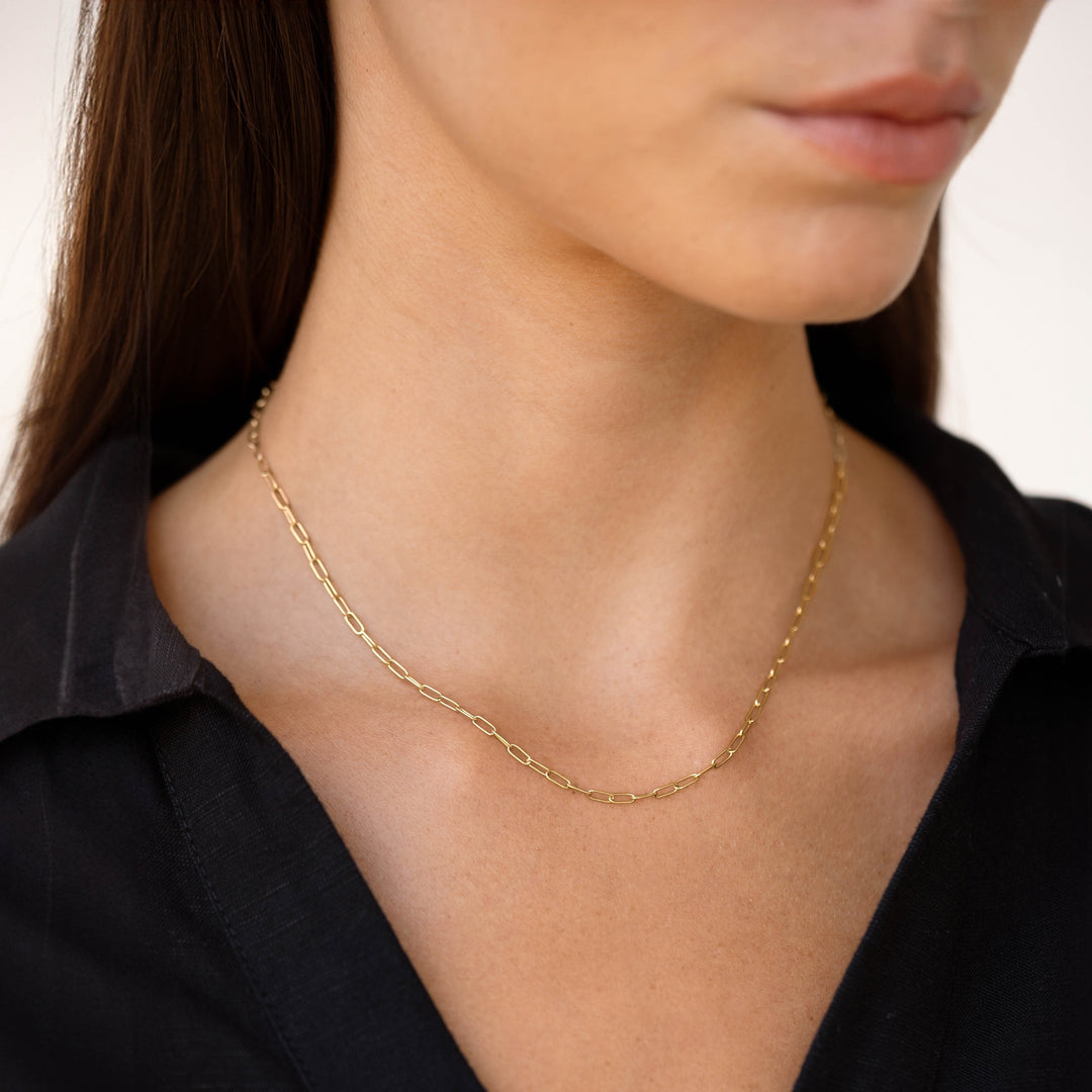Close-up of a woman wearing a Chain Link Necklace 14k Gold with dainty paperclip links and black top on a neutral background