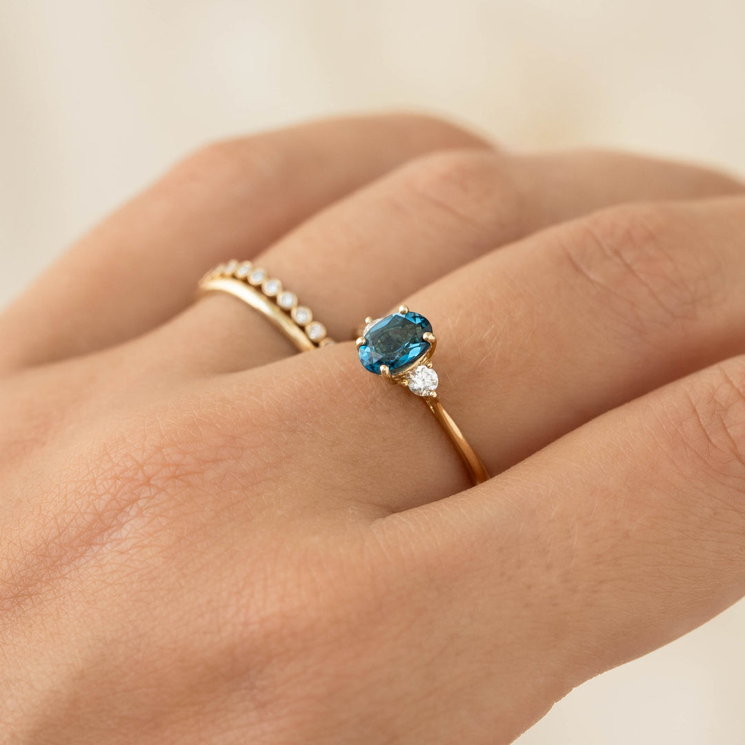 Close-up of hand wearing London Blue Topaz and Diamond Ring 14k Gold - Kindra with two accent diamonds on gold band