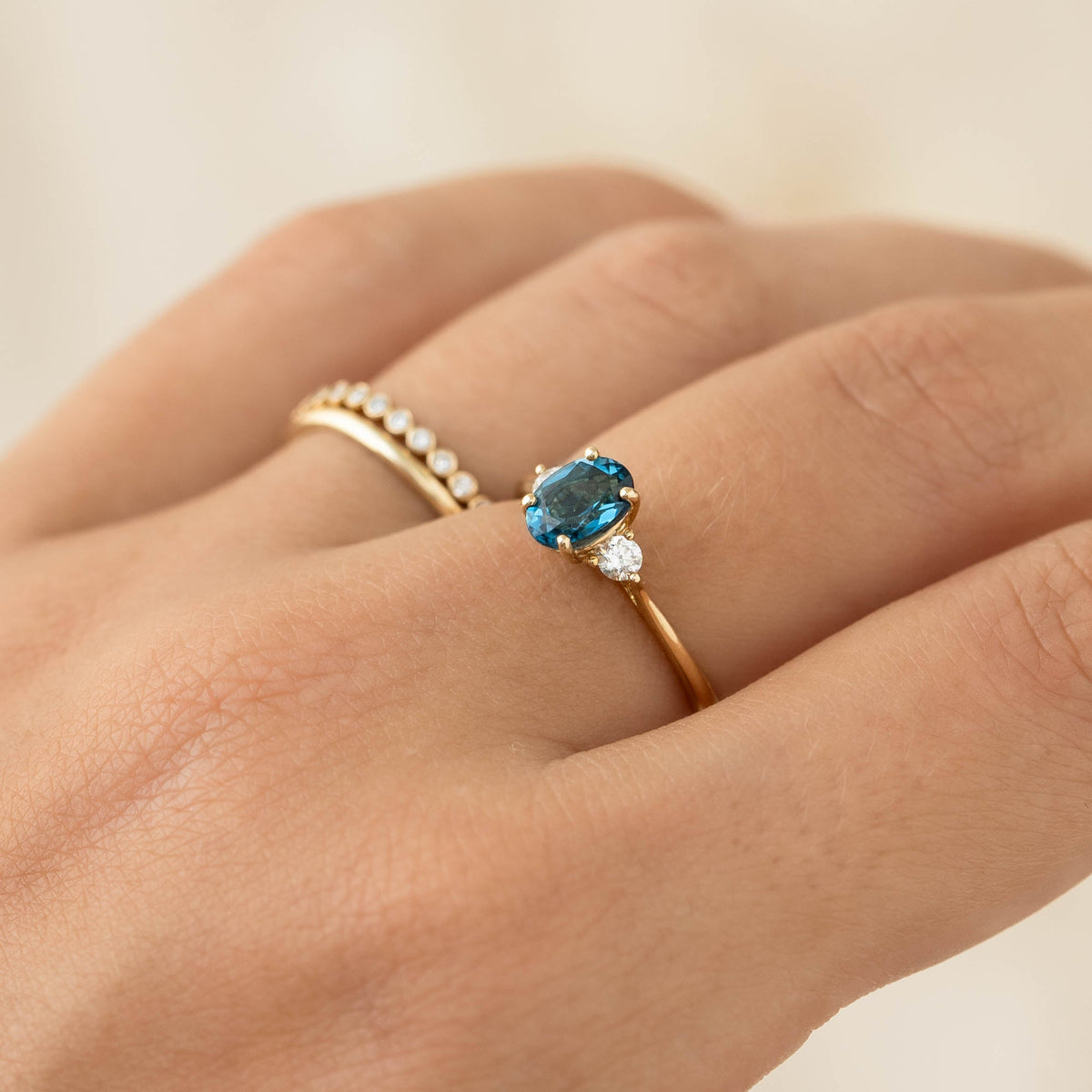 Close-up of hand wearing London Blue Topaz and Diamond Ring 14k Gold - Kindra with two accent diamonds on gold band