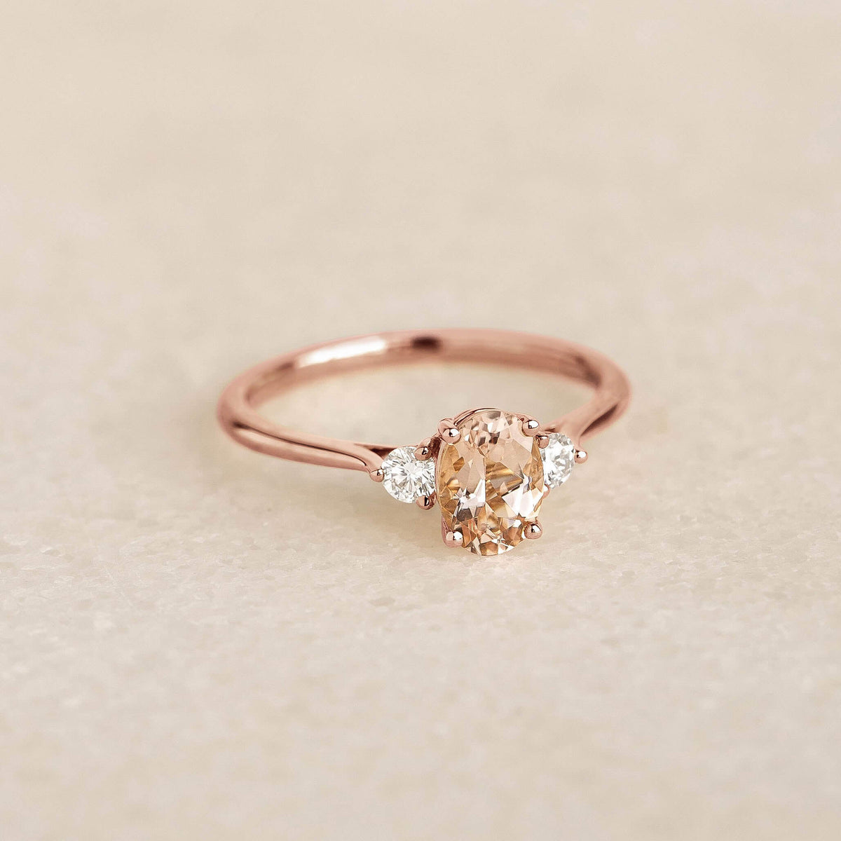 Morganite and Diamond Ring 14k Rose Gold - Kindra with oval morganite and two diamonds on a tapered gold band on soft background