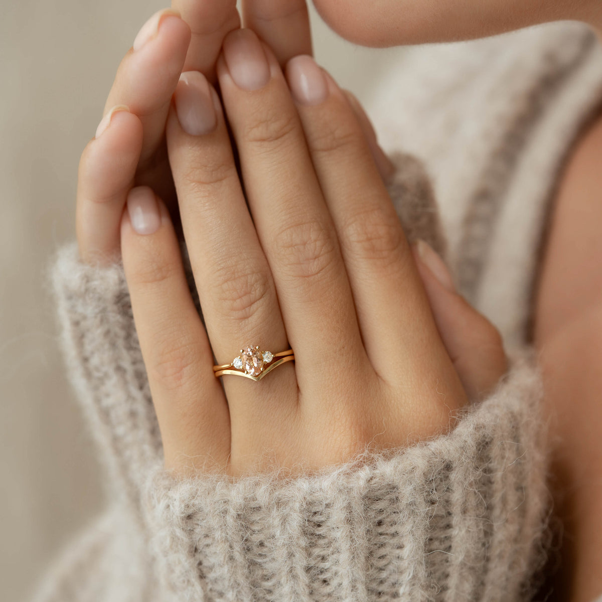Close-up of hands wearing the V Ring 14k Gold - Malva with a beige knit sweater in soft natural light