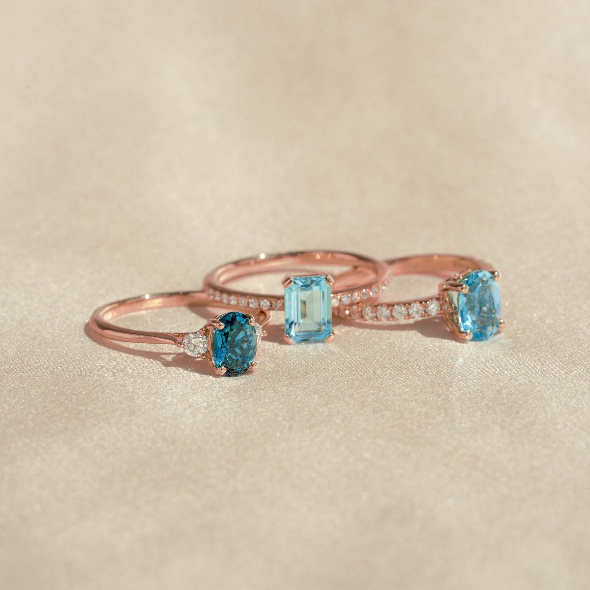 Three rose gold rings featuring oval and emerald cut blue topaz gemstones and diamonds including Oval Swiss Blue Topaz and Diamond Ring Rose Gold - Minette