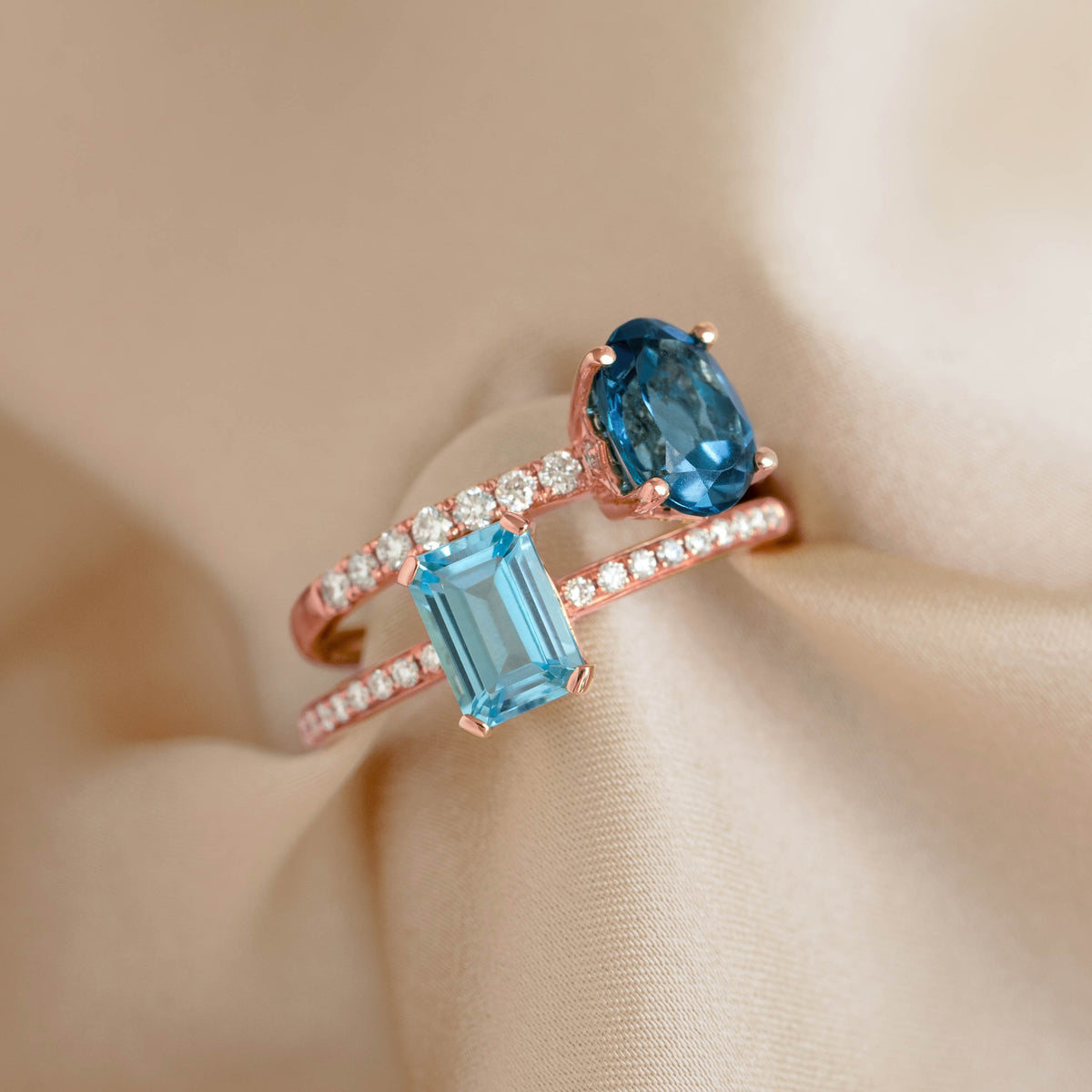 Close-up of Oval London Blue Topaz and Diamond Ring Rose Gold - Minette resting on soft beige fabric background