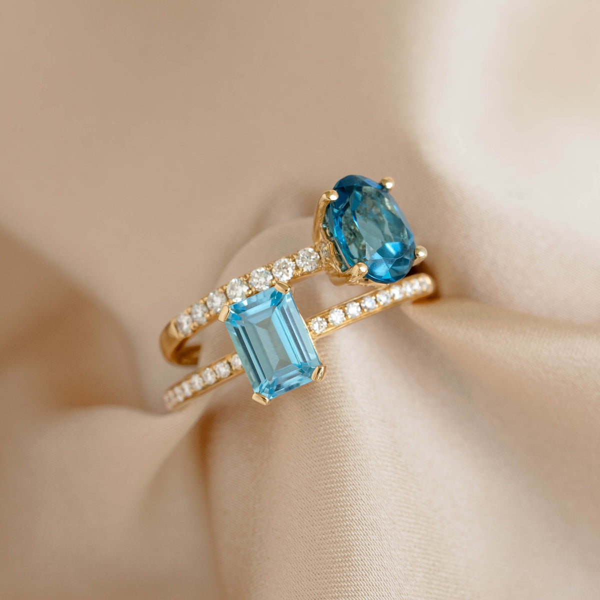 Close-up of the Baguette Swiss Blue Topaz and Diamond Ring 14k Gold - Safiya with blue topaz and diamond accents on beige fabric