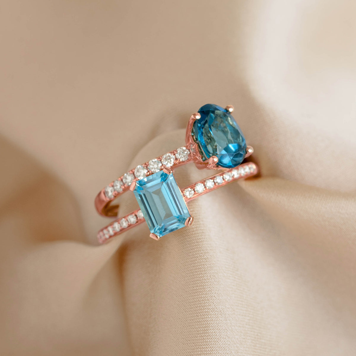 Close-up of Baguette Swiss Blue Topaz and Diamond Ring Rose Gold - Safiya with sparkling diamonds on soft beige fabric background