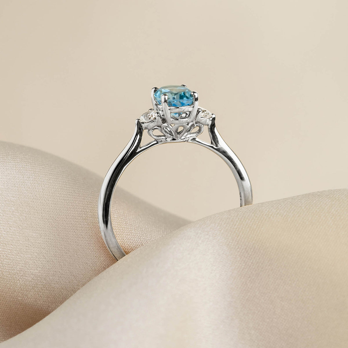 Swiss Blue Topaz and Diamond Ring White Gold - Kindra with oval-cut blue topaz and two side diamonds on satin background